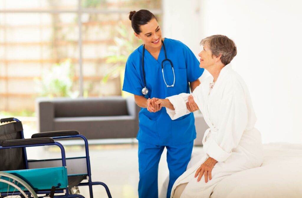 A staff member at an assisted living facility helps someone into their wheelchair.