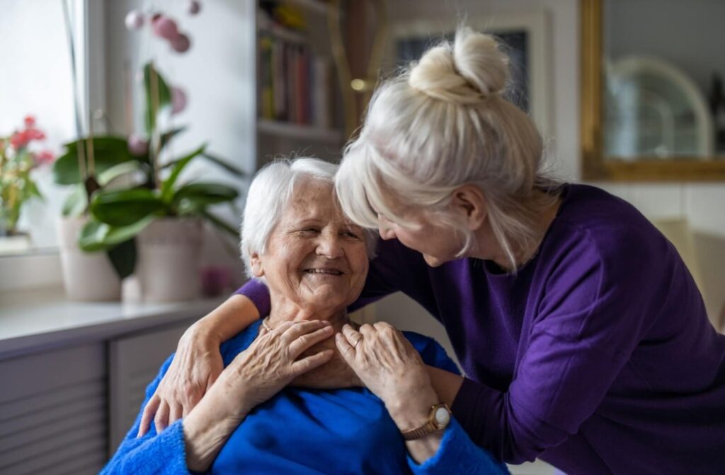An adult hugs their senior parent after visiting their assisted living community.